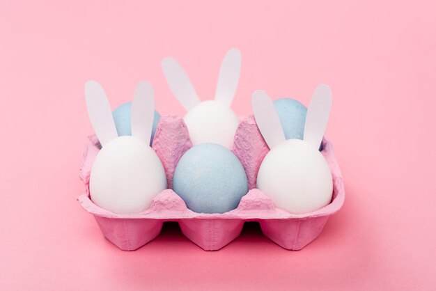 Decorative rabbits and colorful easter eggs on pink background