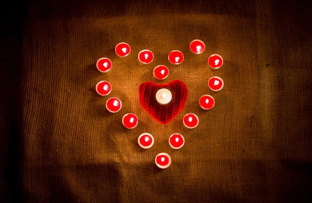 Decorative red candles forming heart shape on linen cloth