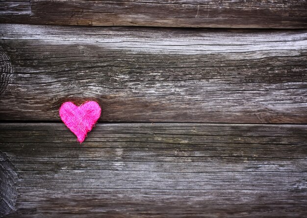 Decorative small heart on wooden old weathered background.