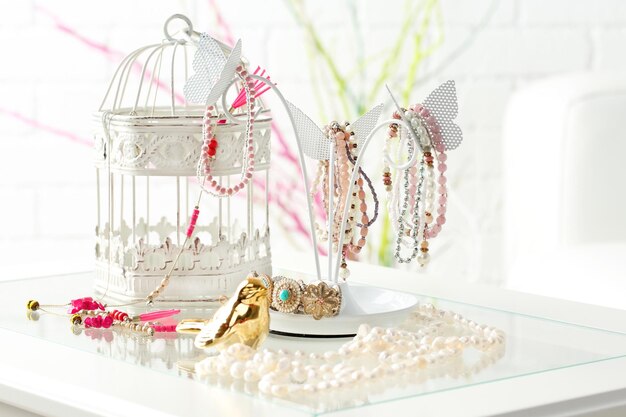 Decorative stand with jewelry and bijouterie on table in room