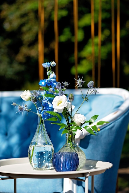 Decorative vases with fresh outdoor flowers, wedding decor in blue colors. Soft selective focus.