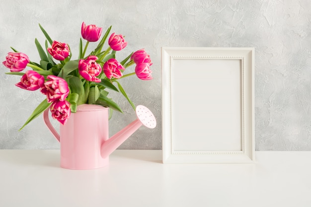 Decorative watering can with pink tulips.