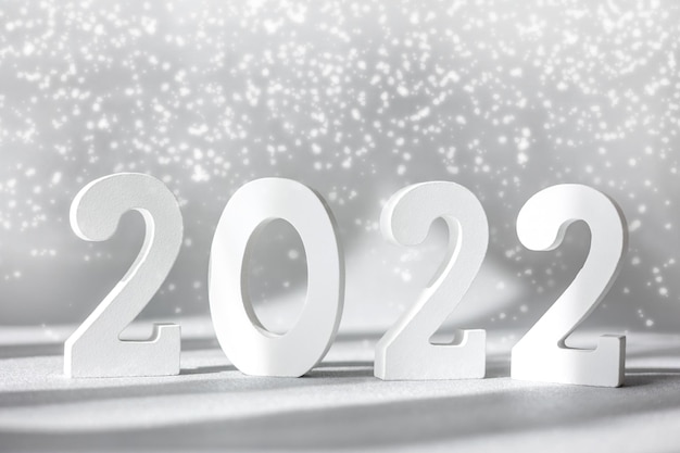 Photo decorative white wooden numbers 2022 isolated on grey background with snow. happy new year 2022. greeting card