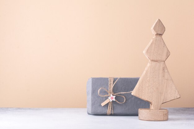 Decorative wooden Christmas tree and star, cone and fabric wrapped gifts, on a light background. Zero waste concept