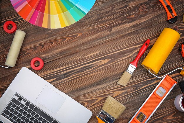 Decorator's tools and laptop on wooden background