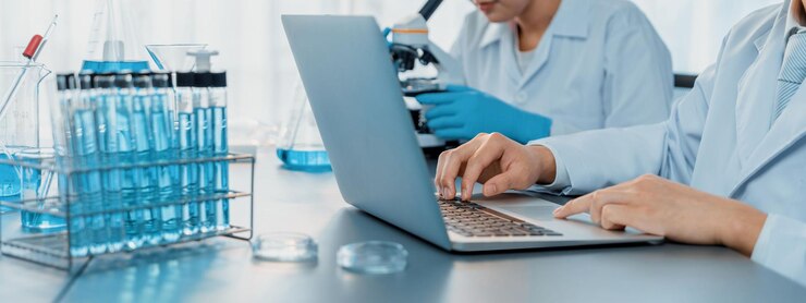 Photo dedicated group of scientist conduct chemical experiments and research in medical lab as groundbreaking developing for new vaccine drug or antibiotic and studying test result on laptop neoteric
