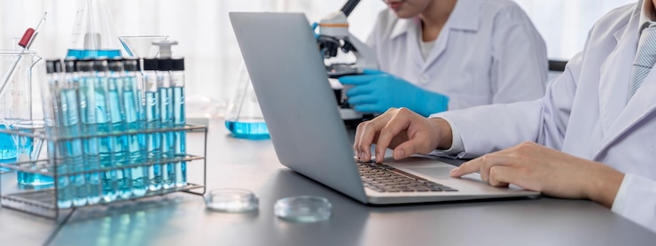 Photo dedicated group of scientist conduct chemical experiments and research in medical lab as groundbreaking developing for new vaccine drug or antibiotic and studying test result on laptop neoteric