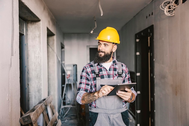 建設過程の建物内でタブレットを使用して仕事をしている専任作業員