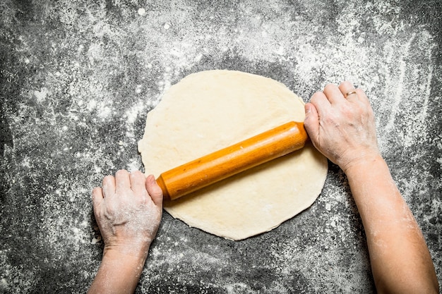 Deeg achtergrond. Het rollen van de handen van vrouwen voor koekjes op rustieke tafel.