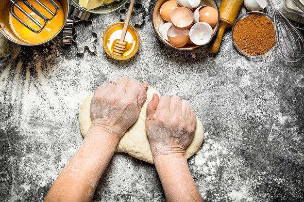 Deeg achtergrond. Vrouw kneedt deeg met verschillende ingrediënten op tafel. Op rustieke achtergrond.