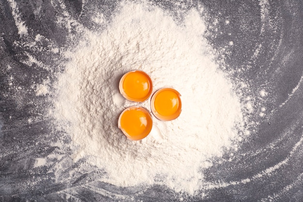 Deeg bakken en koken achtergrond meel en eieren op een donkere houten keuken achtergrond als ingrediënten voor een recept en deeg gerechten hoge kwaliteit foto