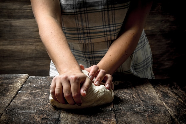 Foto deeg tafel. een vrouw bereidt een deeg voor. op een houten tafel.