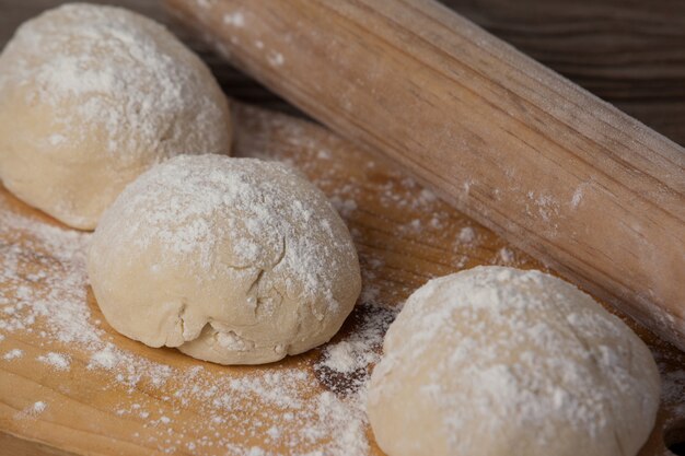 Deegroller met pizzadeeg en bloem op snijplank