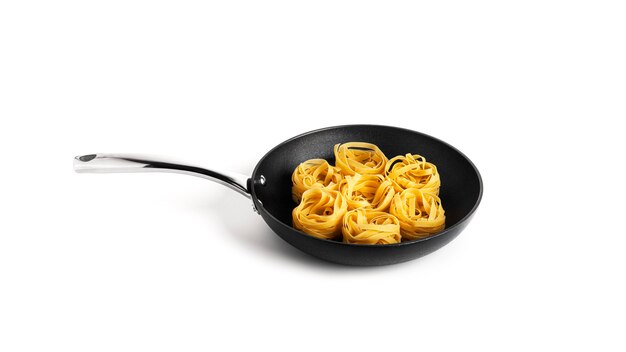 Deegwaren nesten in een koekenpan op wit wordt geïsoleerd. Fettuccine-pasta.