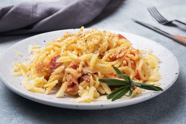 Deegwarenspaghetti met de kaas van het baconei op een plaat met kruiden. Traditioneel Italiaans gerecht Carbonara. Grijze betonnen tafel