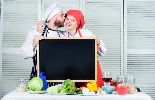 Deel vreugde Man en vrouw chef-kok koken samen eten Paar met schoolbord voor advertentie Mooie familie in de keuken Familie restaurant Familiedag Paar verliefd samen koken Familie waarden