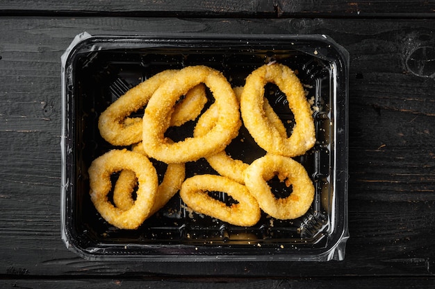 Photo deep fried calamari rings pack set, on black wooden table background, top view flat lay