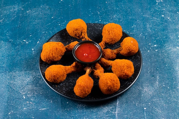 Deep fried Chicken Lolipop or Chicken drumstick with tomato sauce and mayo dip served in a dish isolated on background side view