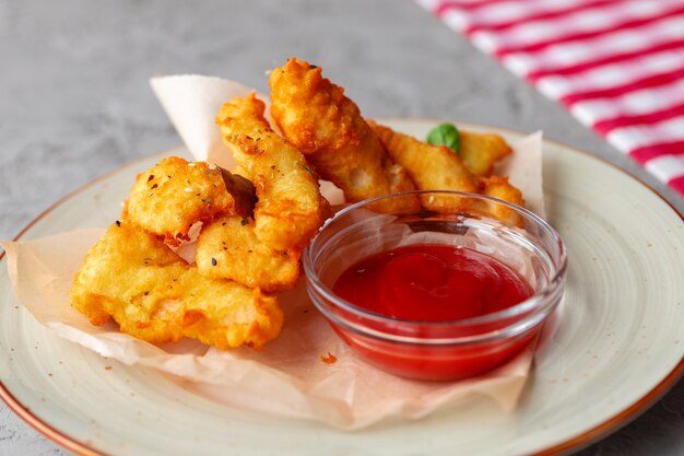 Deep fried chicken nuggets with sauce served on table