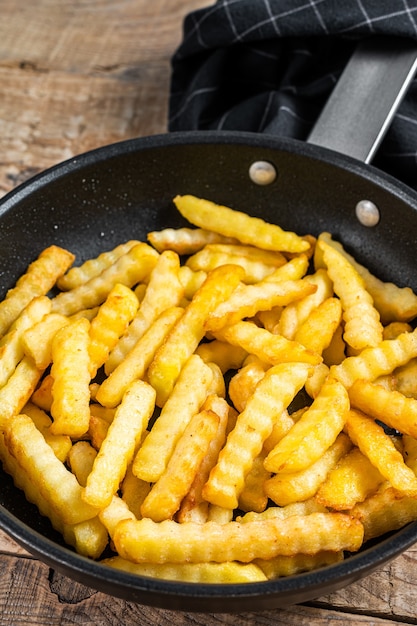 Deep fried Crinkle French fries potatoes sticks in a pan