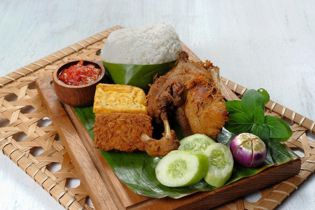 Anatra fritta servita con riso, verdure e sambal (nasi bebek) - stile alimentare indonesiano.