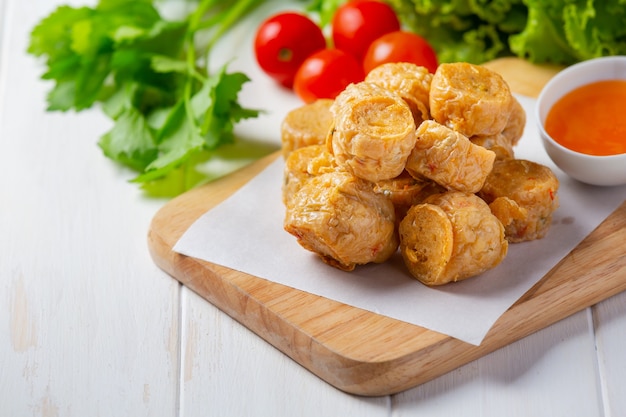 Rotolo di fhicken fritto in profondità sulla superficie di legno bianca.