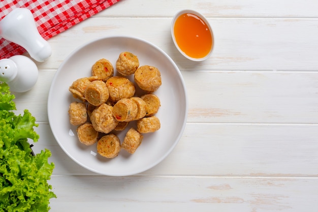 Rotolo di fhicken fritto in profondità sulla superficie di legno bianca.