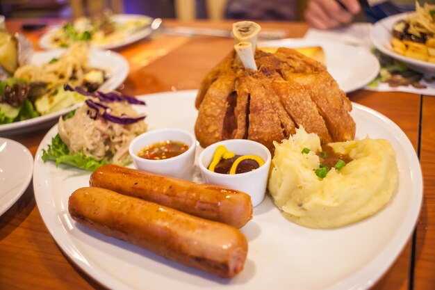 Deep fried pork knuckle on a white plate with side dishes