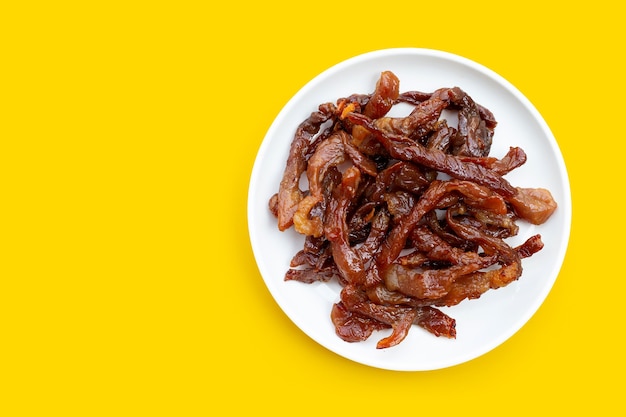 Deep fried sun-dried pork on yellow wall.