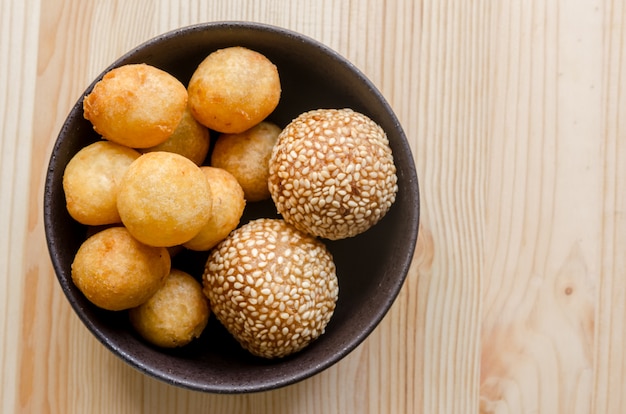 Deep fried sweet potato balls in black bowl on wooden table