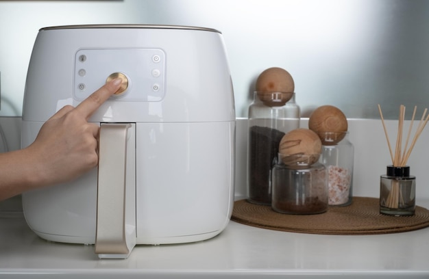 deep fryer machine in modern home kitchen. the hand that adjusts the fryer machine.