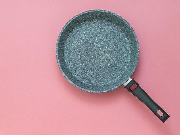 A deep gray frying pan on a bright red background The view from the top