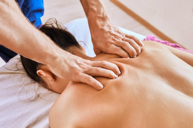 Photo deep tissue massage therapy for young caucasian woman lying face down on massage table