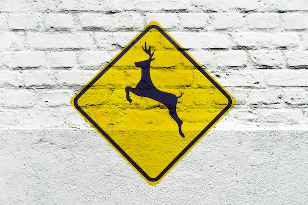 Deer crossing: traffic sign stamped on the white wall, like graffiti