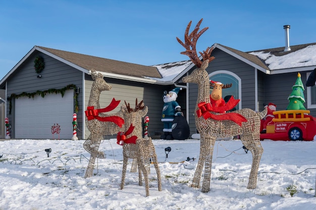 Deers figures with red bows in the garden near the house. Outdoor Christmas decorations