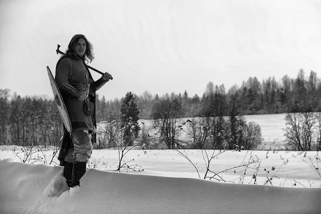 Защитник молодой воин в кольчужных доспехах, вооруженный мечом и топором