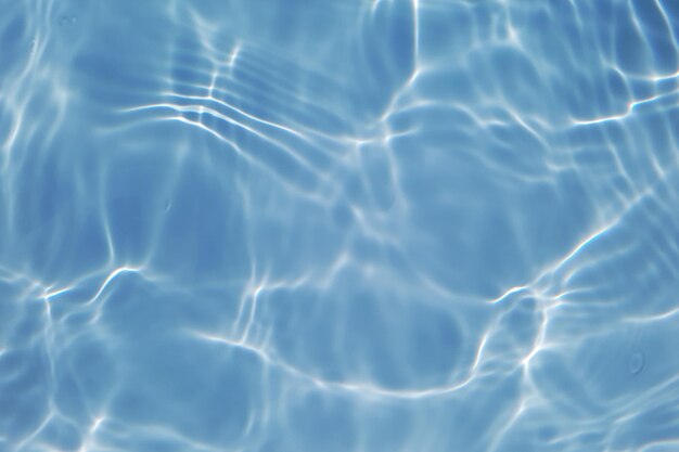 デフォーカスぼやけた透明な青い色の澄んだ穏やかな水面のテクスチャーと水しぶきと泡 トレンディな抽象的な自然の背景 コピースペースで日光の下で水の波 輝く青い水彩画