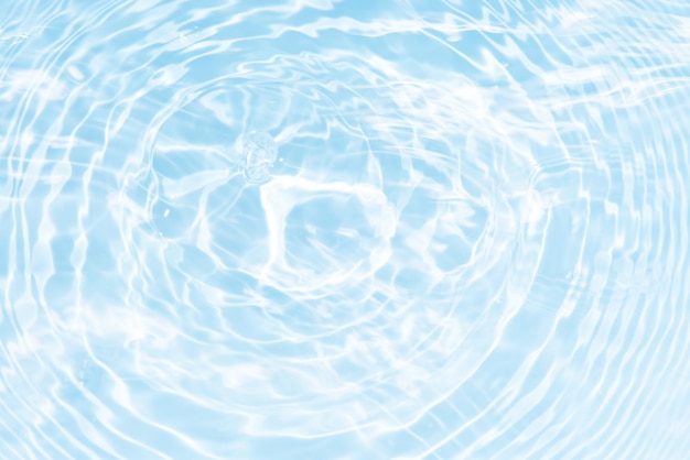 Defocus blurred transparent blue colored clear calm water surface texture with splashes reflection