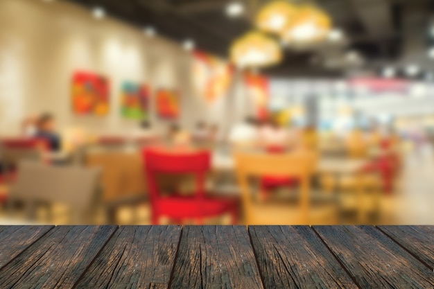 Photo defocus inside of restaurant with wood table at foreground.