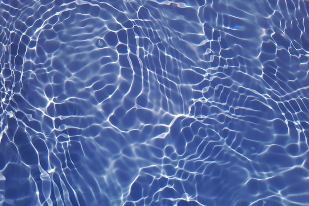 Defocus wazig transparant blauw gekleurd helder kalm wateroppervlak textuur met spatten en bubbels Trendy abstracte natuur achtergrond Watergolven in zonlicht met kopieerruimte Blauwe aquarel schijnt