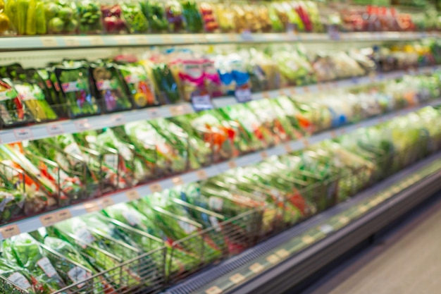 Sfocatura sfocata su uno scaffale della spesa verdura e frutta messi su di essi al cibo nel supermercato.