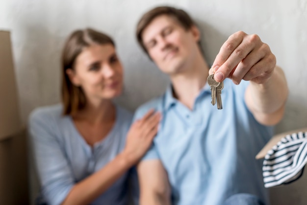 Photo defocused couple holding keys to old house before moving out