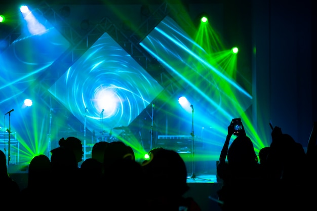 Defocused entertainment concert lighting on stage with people silhouette