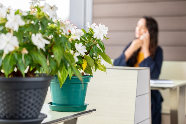 Foto freelancer distratto che parla al cellulare in un caffè con dei fiori