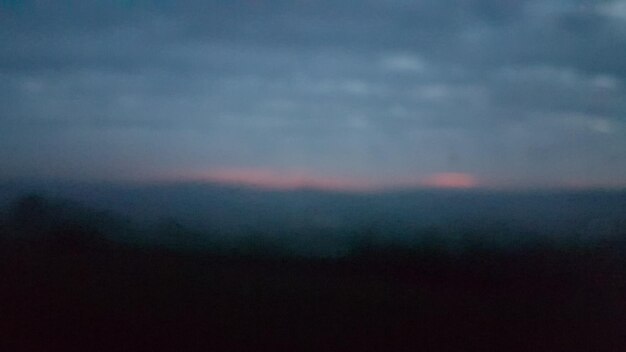 Defocused image of fog against sky at sunset