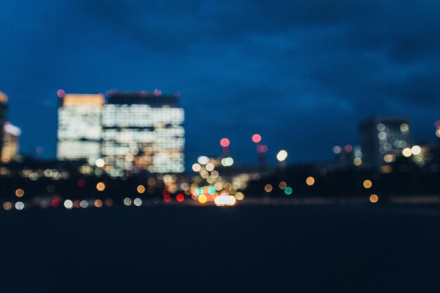 Photo defocused image of illuminated city against sky at night