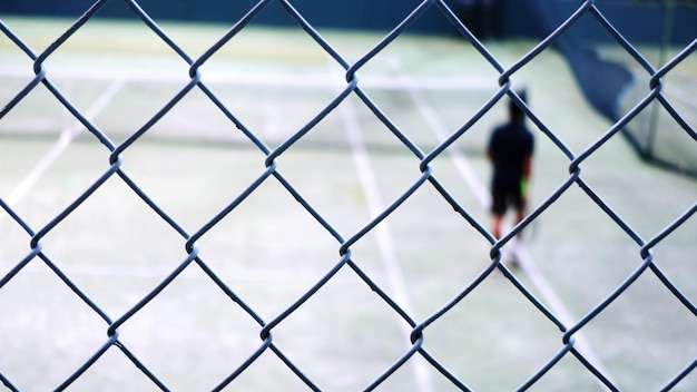 사진 체인링크 울타리 를 통해 볼 수 있는 코트 에 있는 테니스 선수 의 초점 이 분해 된 이미지