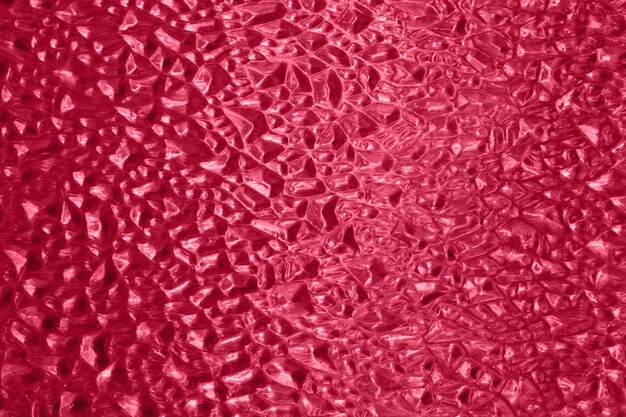 Defocused photography of glass texturecolored in tredny red color of 2023