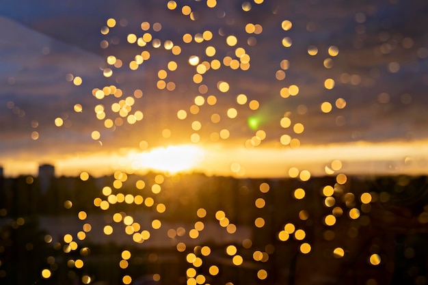 Gocce di pioggia sfocate sulla finestra di vetro durante il tramonto