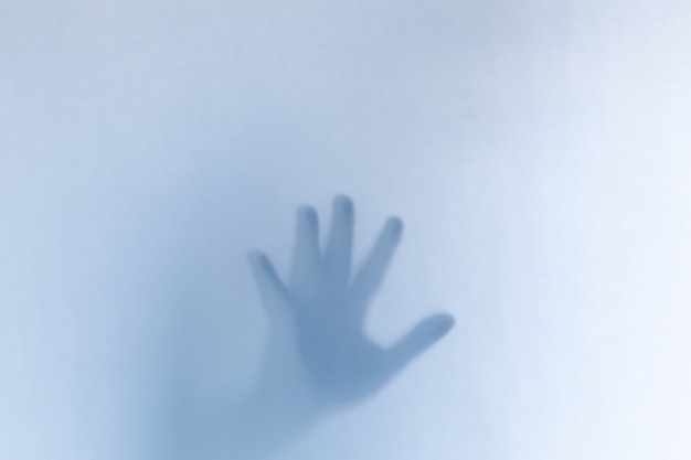 Mani fantasma spaventose defocused dietro un vetro bianco